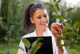 smiling agronomist with notebook standing in apple orchard