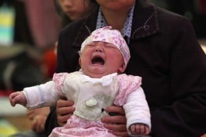 This photo taken on April 23, 2013 shows 4-month-old Li Jie crying in her mother's arms inside a temporary settlement in Lingguan township of Baoxing county in Yaan, southwest China's Sichuan province.  Tens of thousands of homeless survivors of China's devastating quake are living in makeshift tents or on the streets, facing shortages of food and supplies as well as an uncertain future.   CHINA OUT   AFP PHOTO        (Photo credit should read AFP/AFP/Getty Images)
