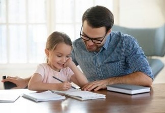 Young father in eyeglasses pleased to see little daughters' study success. Excited smiling small child girl enjoying learning with pleasant dad at home. Children education, home schooling concept.