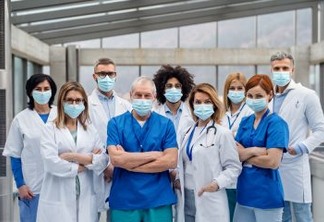A group of doctors with face masks looking at camera, corona virus concept.
