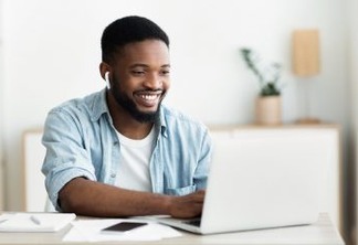 Smiling african-american guy in earphones studying foreign language online through video conference application, panorama with copy space