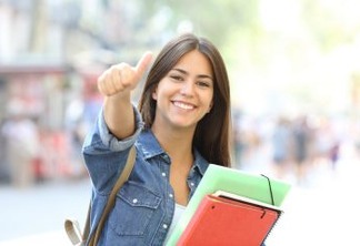 Happy student posing with thumbs up looking at you in the street