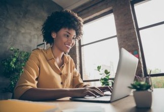 Photo of cheerful positive business lady smiling toothily looking into screen of notebook, computer comparing corporate income for previous year with current one