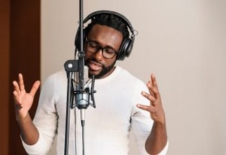 African young man singing on musical studio.