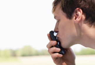 Man kissing cell phone outdoors