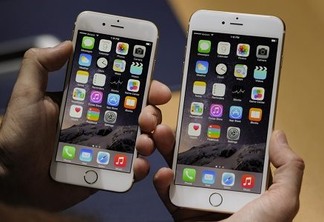 An attendee displays the new Apple Inc. iPhone 6, left, and iPhone 6 Plus for a photograph after a product announcement at Flint Center in Cupertino, California, U.S., on Tuesday, Sept. 9, 2014. Apple Inc. unveiled redesigned iPhones with bigger screens, overhauling its top-selling product in an event that gives the clearest sign yet of the company's product direction under Chief Executive Officer Tim Cook. Photographer: David Paul Morris/Bloomberg via Getty Images