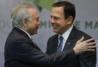 Brazil's President Michel Temer, left, embraces Sao Paulo Mayor Joao Doria, during a ceremony to announce the creation of a new park and museum at the City Hall, in Sao Paulo, Brazil, Monday, Aug. 7, 2017. (AP Photo/Andre Penner)
