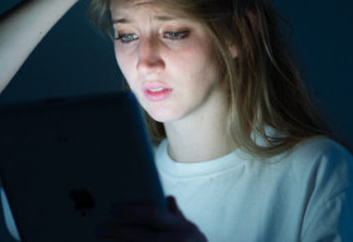 D9KFCD A young woman using tablet computer iPad looking worried anxious concerned scared frightened sad upset tearful depressed bullied