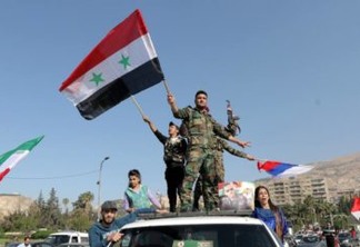XYB05. Damascus (Syrian Arab Republic), 14/04/2018.- Syrian soldiers wave national flags along with Iranian and Russian flags as people gather to show support for the Syrian government in Umayyad square in Damascus, Syria, 14 April 2018. The gathering was held to show solidarity with the Syrian army and regime hours after the USA, Britain and France bombed multiple government targets in Syria in an operation targeting alleged chemical weapons sites. (Damasco, Atentado, Protestas, Siria, Rusia, Francia, Estados Unidos) EFE/EPA/YOUSSEF BADAWI