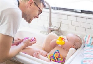 Dad gives his young infant daughter a bath in the sink