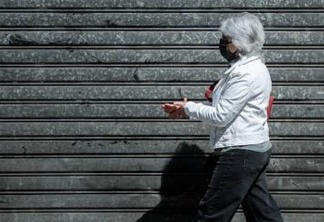 A woman  wearing a face mask washes her hands as she walks on May 12, 2020, in Paris, two days after France eased lockdown measures to curb the spread of the COVID-19 pandemic, caused by the novel coronavirus. (Photo by JOEL SAGET / AFP)