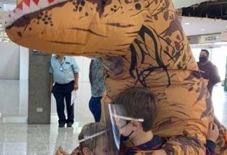 Mãe se fantasia de dinossauro para se proteger da Covid-19 e receber filhos em aeroporto