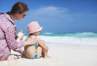 Mother applying sunblock cream on her daughters shoulder