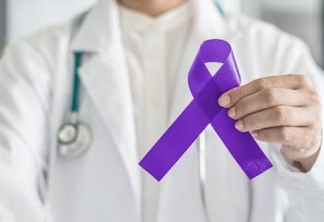 Purple violet ribbon symbolic bow color on doctor's hand support for Hodgkin's lymphoma and testicular cancer awareness