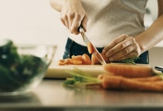 Mid Section View of a Young Woman Cutting a Carrot on a Chopping Board at a Kitchen Counter