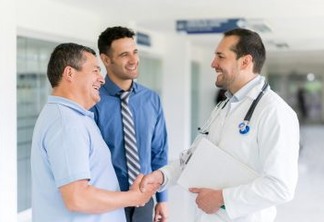 Doctor greeting patient with a handshake at the hospital and medical insurance agent standing there