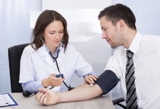 Female Doctor Checking Blood Pressure Of Young Businessman