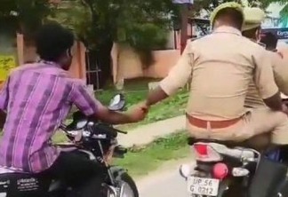 Policial na garupa conduz detido a delegacia segurando a mão dele, que guia outra moto - VEJA VÍDEO