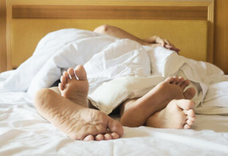 Couple on white bed in hotel room focus at feet