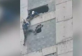 Operário fica pendurado em prédio e colegas quebram parede para salvá-lo