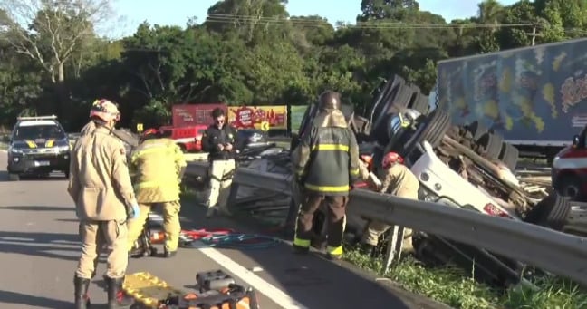 Carreta carregada de madeira tomba e deixa motorista preso às ferragens na BR-230 em Santa Rita